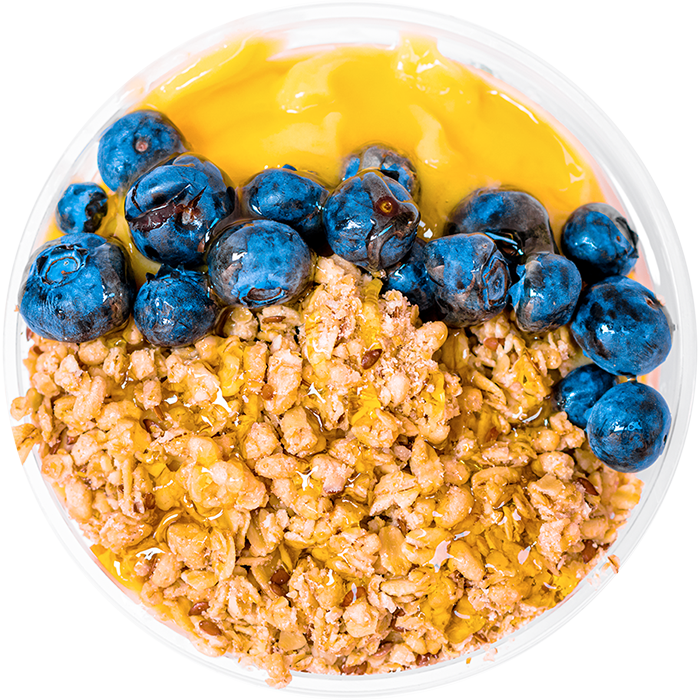 Granola, blueberry, and honey toppers on a yellow smoothie bowl.